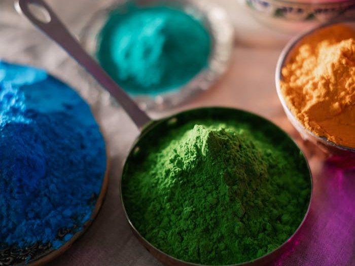 Assorted colorful powders for Holi festival arranged in decorative bowls with vibrant hues.