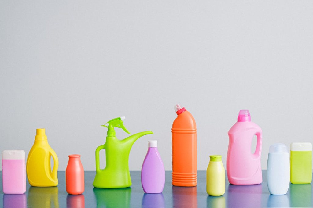 composition-of-detergents-on-table-5217889 A vibrant assortment of cleaning product containers arranged on a reflective surface, perfect for household sanitation themes.