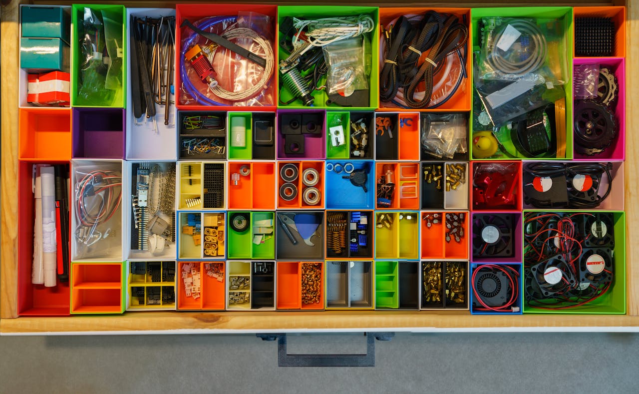 creative-03 Top view of a neatly organized drawer filled with colorful containers holding various tools and electronic parts.