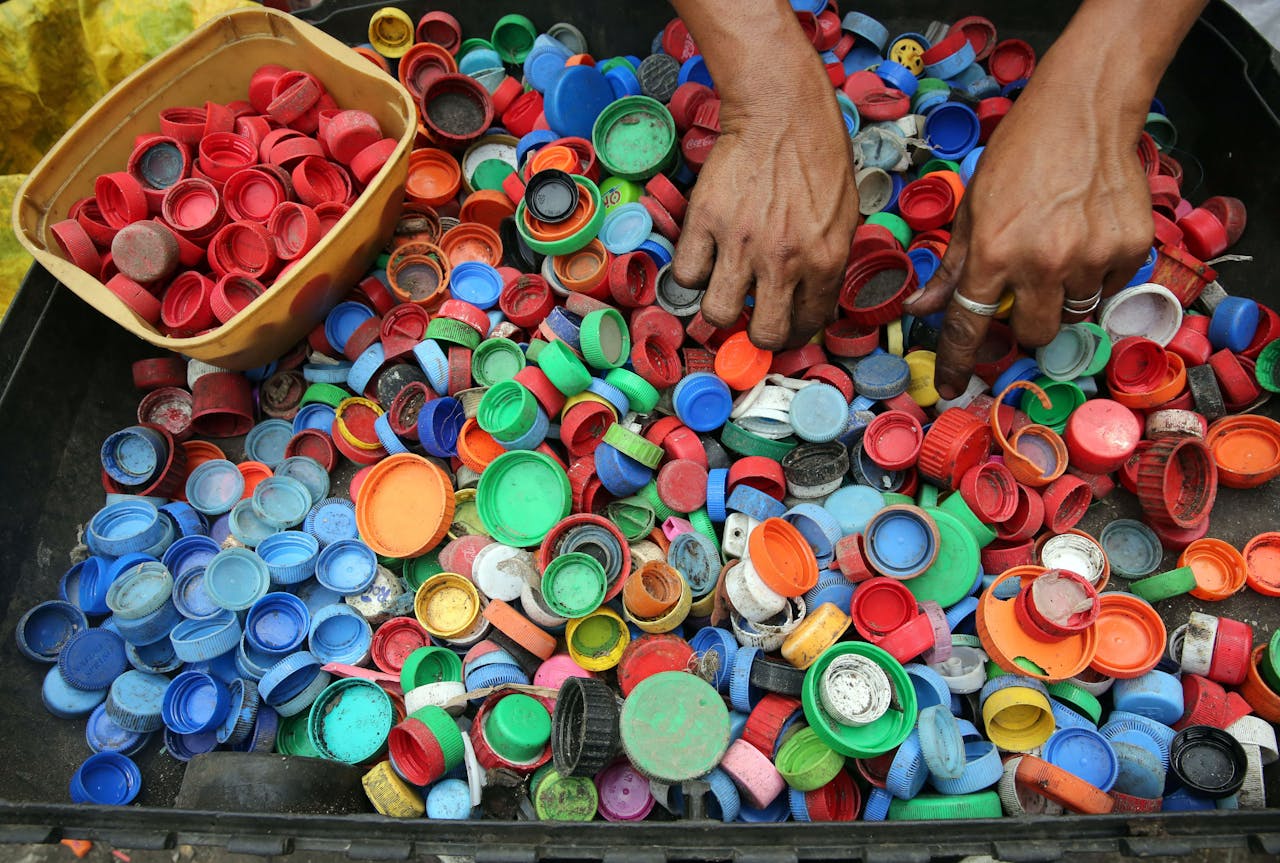 mobile-01 A vibrant assortment of plastic bottle caps being sorted by hand for recycling in Manila.